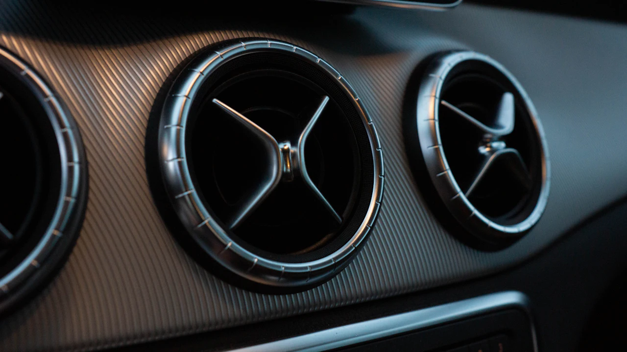 Three round chrome air vents set into a textured dashboard, photographed close in low light