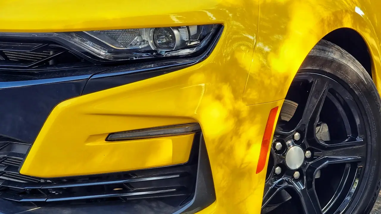 The front bumper and black alloy wheel of a yellow sports car.