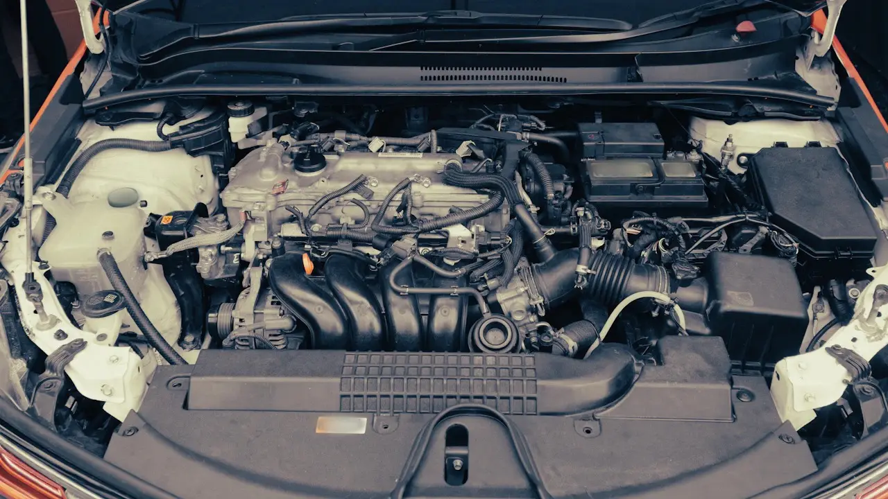 A modern engine bay under an open bonnet, the 12-volt battery at the right; labels blurred.