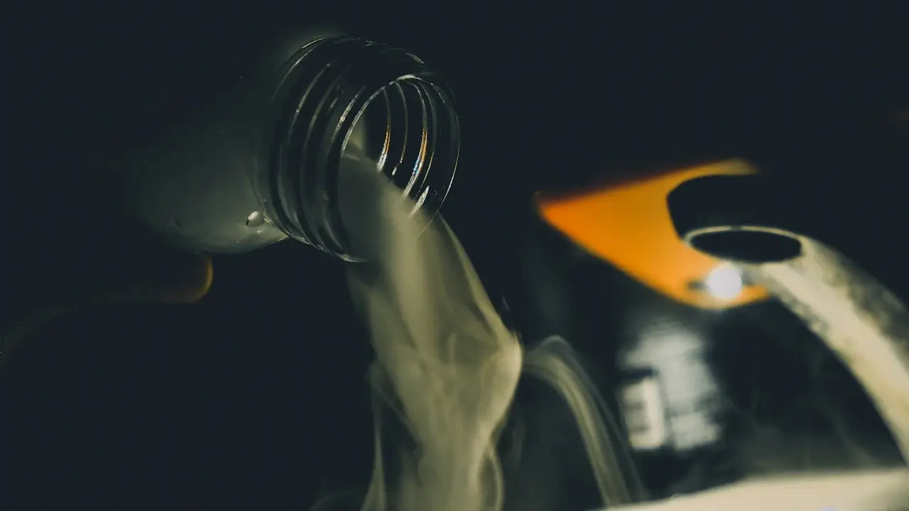 Motor oil being poured from a bottle into an engine's filler neck.