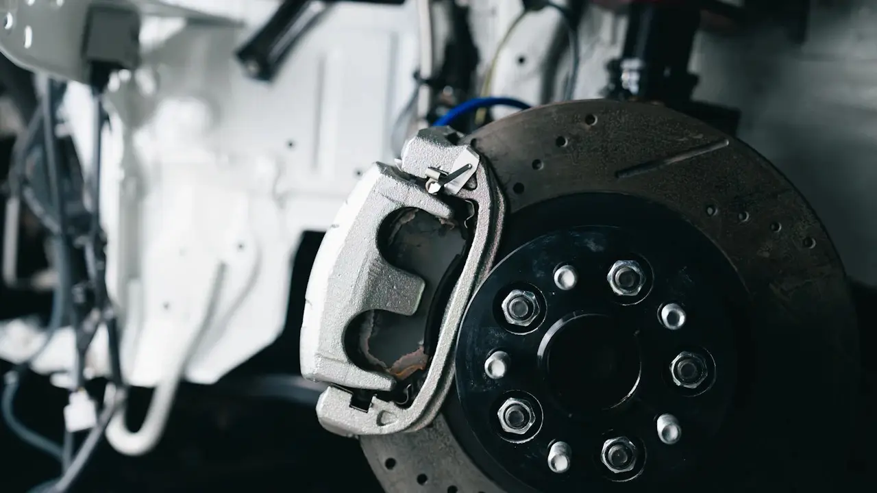 A brake caliper on a drilled brake rotor with the wheel removed.