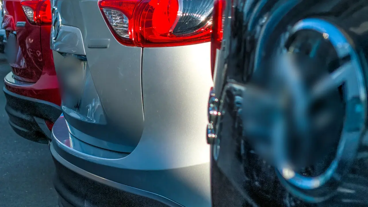Close view of the rear bumpers of cars parked tightly in a row.
