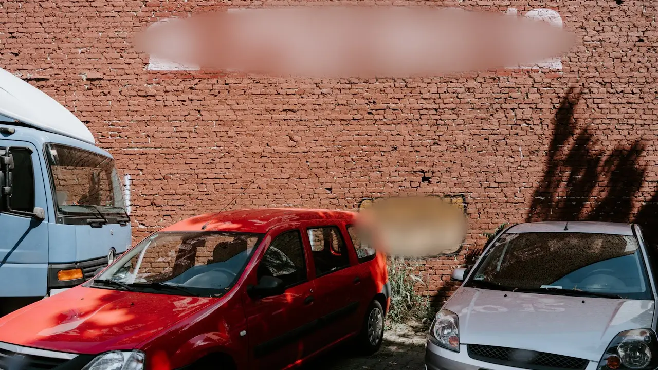 Two used cars parked against a brick wall.