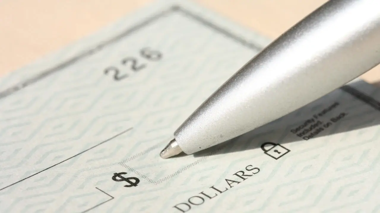 A pen poised over a paper check.