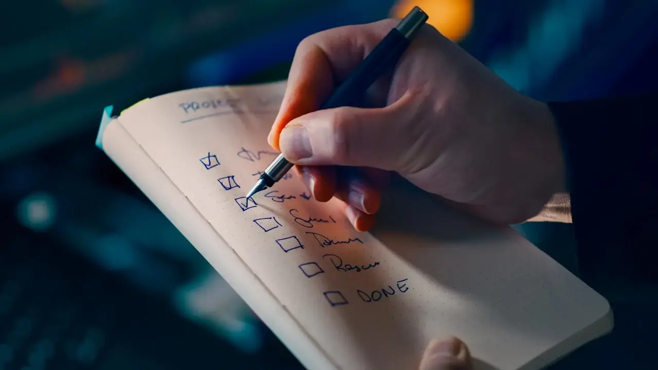A hand ticking boxes on a handwritten checklist.