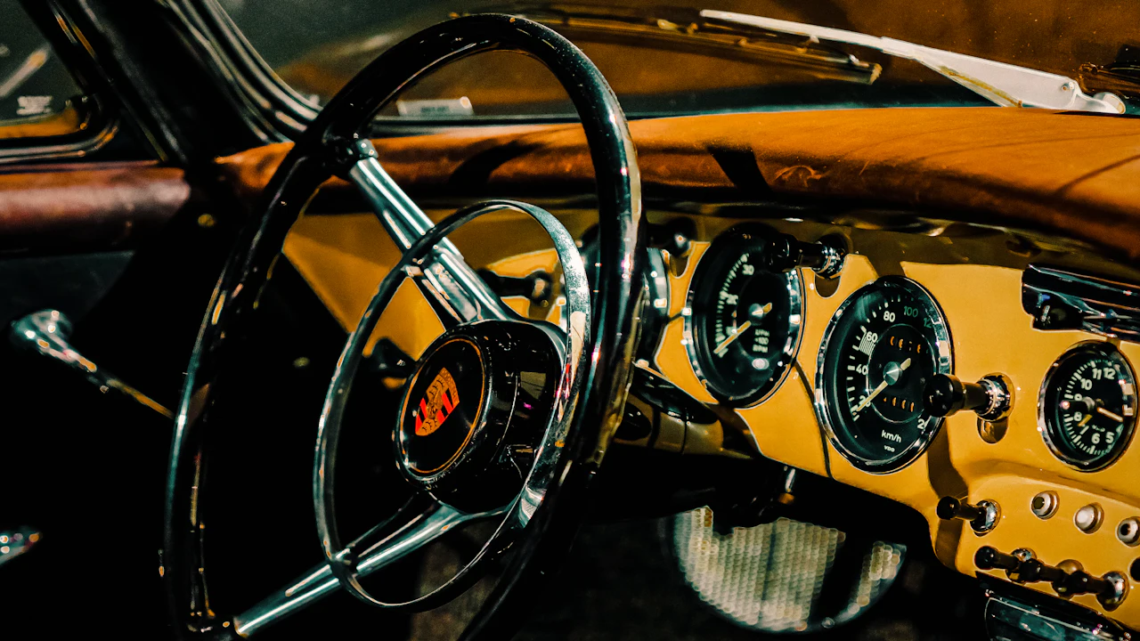 The dashboard and steering wheel of an old car, gauges visible behind the wheel