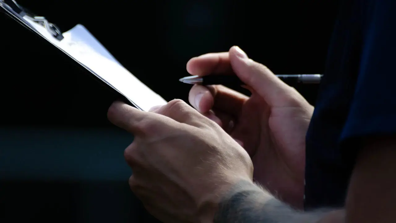 A hand holding a pen over a clipboard.