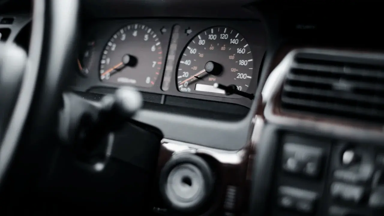 An analogue instrument cluster with tachometer and speedometer, seen past the steering wheel.