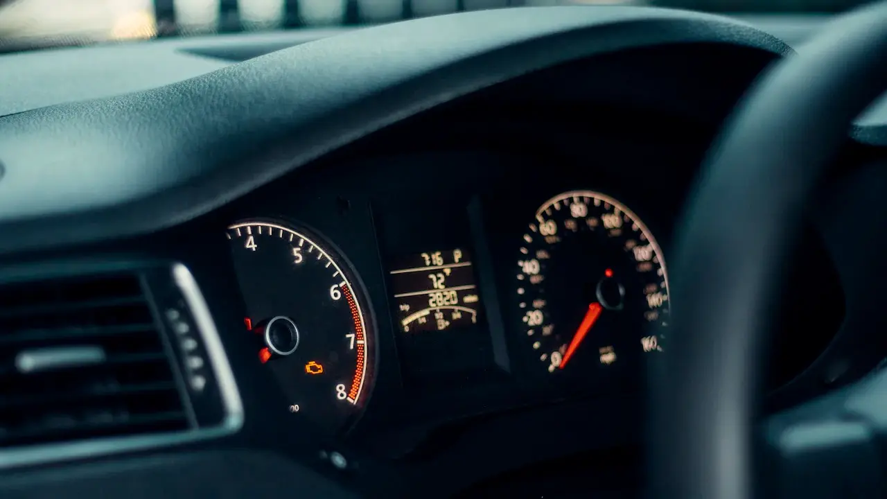 A car’s instrument cluster with the odometer readout and an amber engine warning light lit.