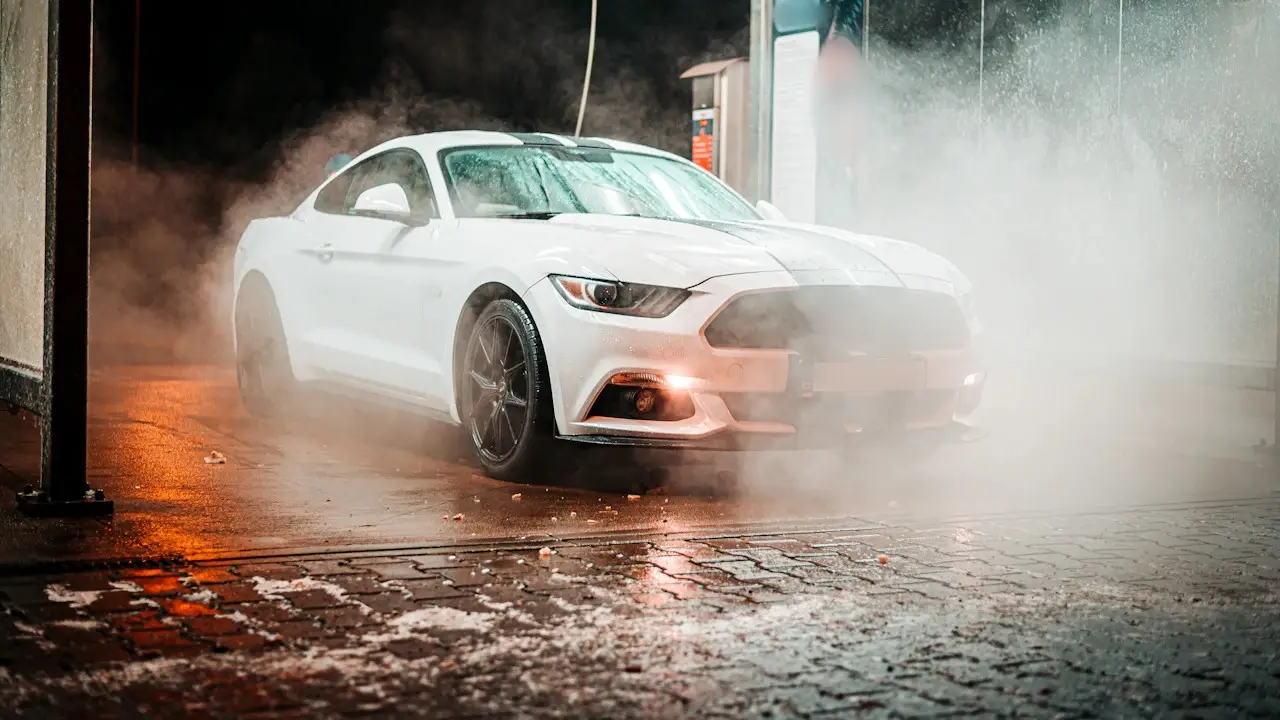 A white coupe in steam at a wash bay.