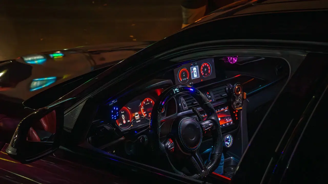 A car dashboard lit at night, with a centre screen, add-on gauges and the instrument cluster.