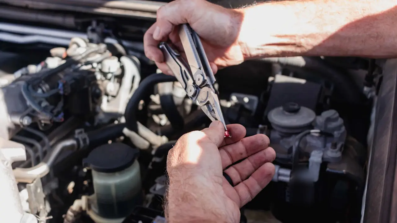 Hands working in an open engine bay beside a coolant reservoir and an oil filter.