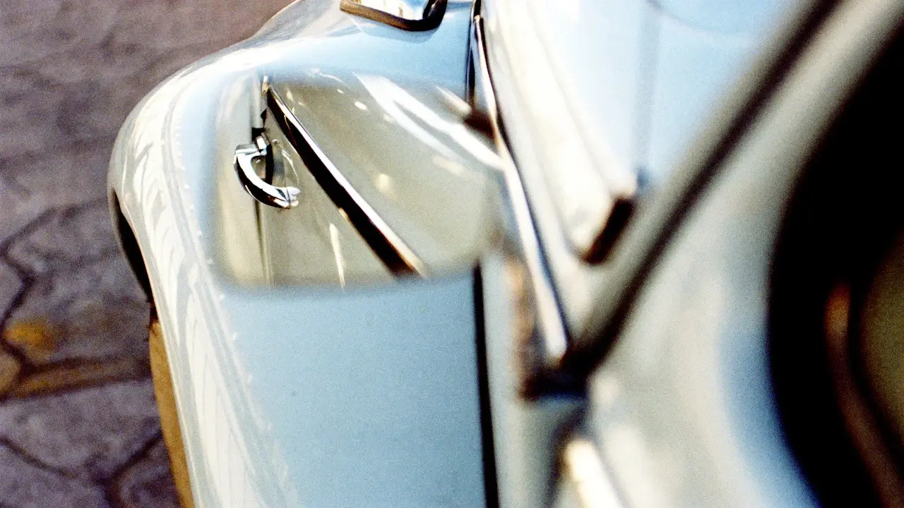 Close view of a pale blue car's door handle and door edge.