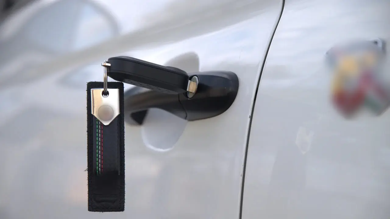 A flip key with a fabric tag in a car’s door lock.