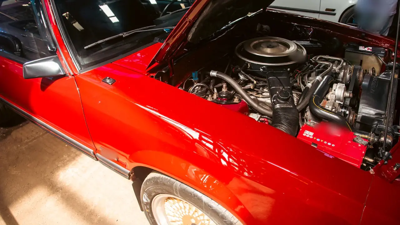 An older V8 car with its hood open at a show.