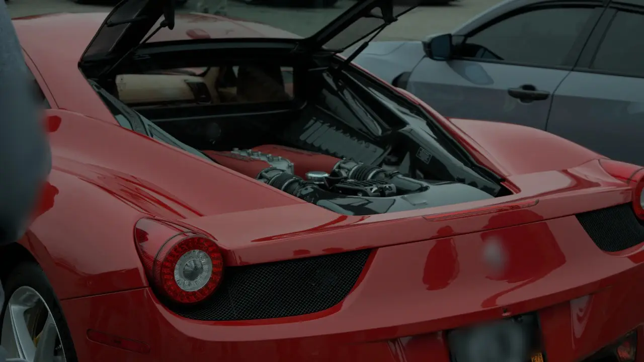 A red mid-engine sports car with its engine lid raised.
