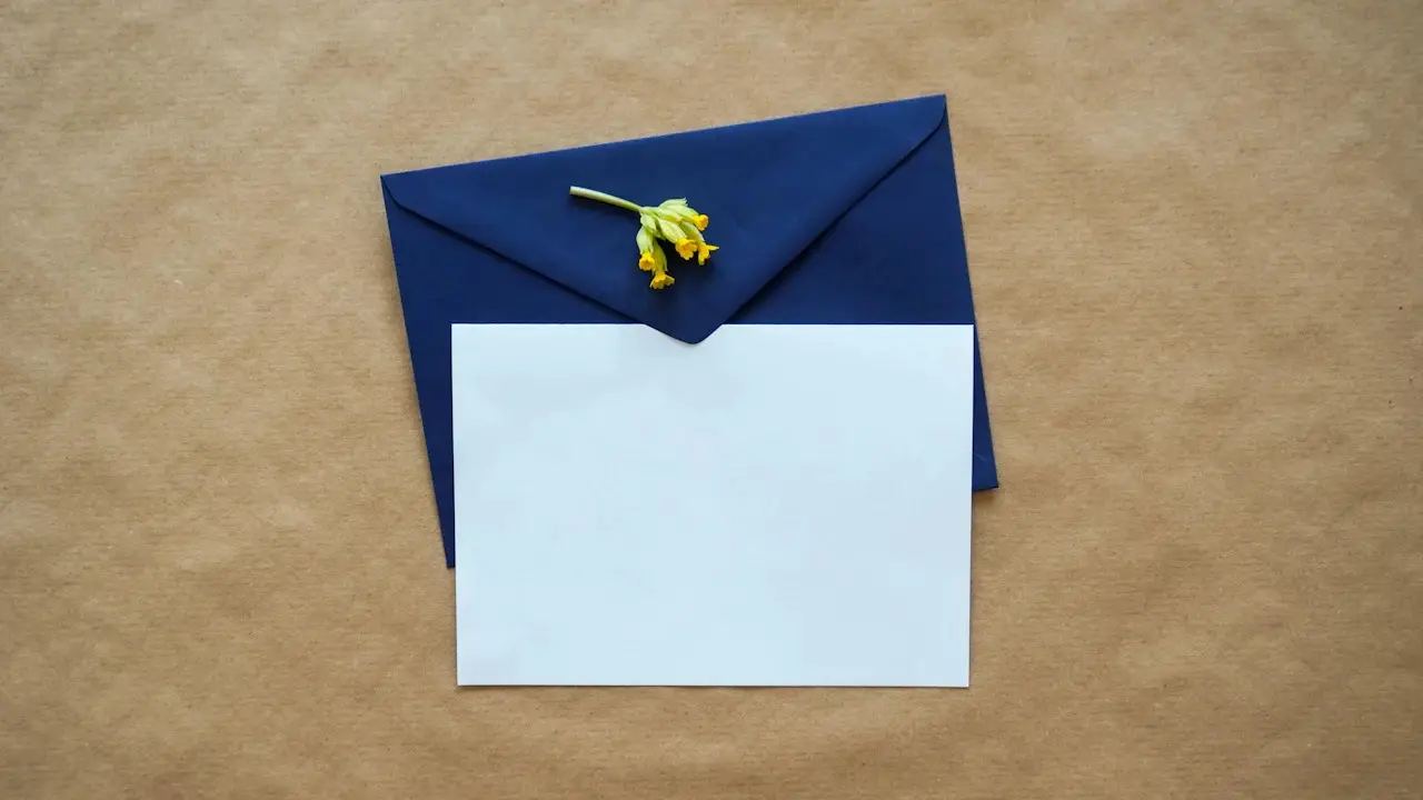 A blue envelope with a blank white card on brown paper, seen from above.