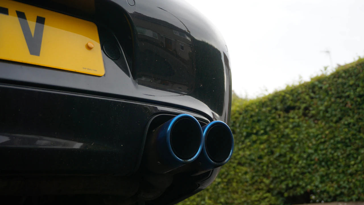 Twin blue-rimmed exhaust tips under the rear bumper of a dark car