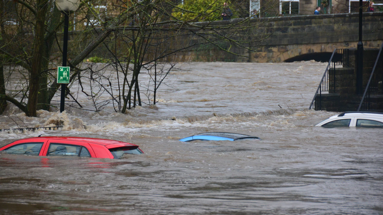 Cars submerged to the windows in brown flood water on a town street