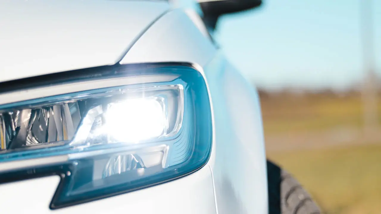 Close view of a white car's LED headlight and front wing.