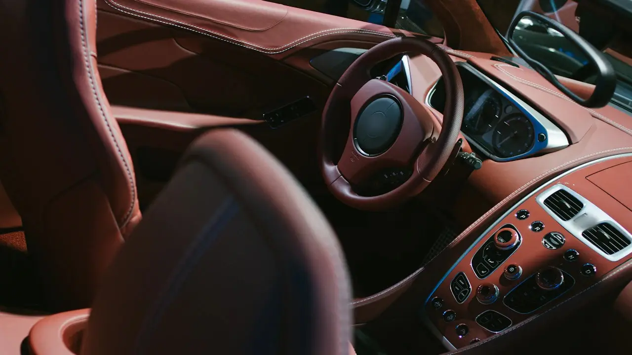 A car’s leather interior with the steering wheel, gauges and center console.