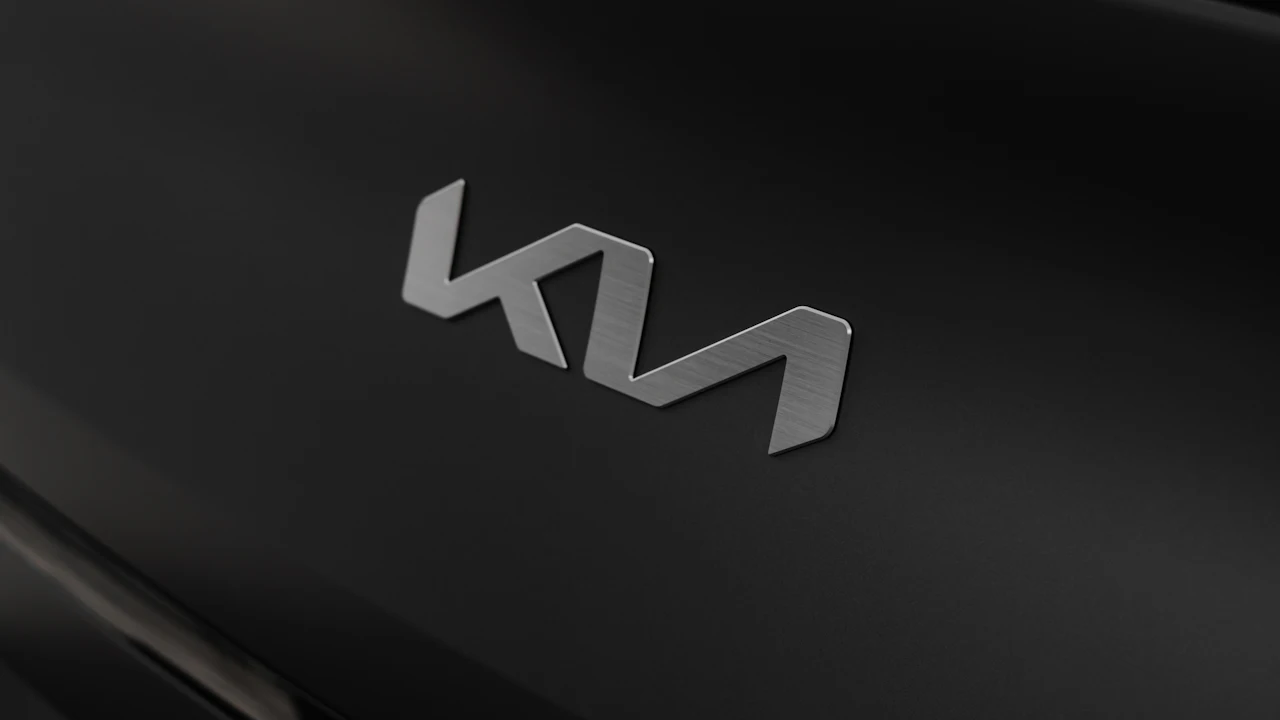 The brushed-metal Kia badge set into a black bonnet, photographed close at an angle