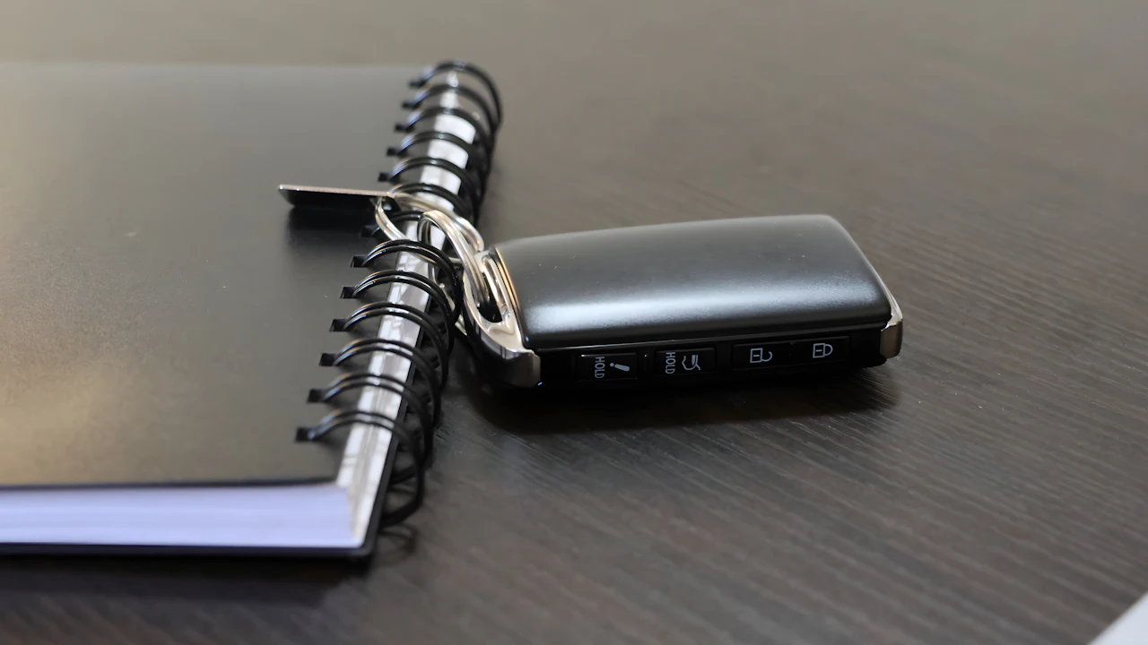 A car key fob resting on a closed notebook on a dark desk