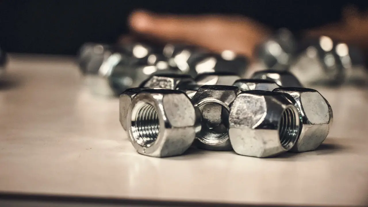 Chrome wheel lug nuts piled on a workbench, in close-up.