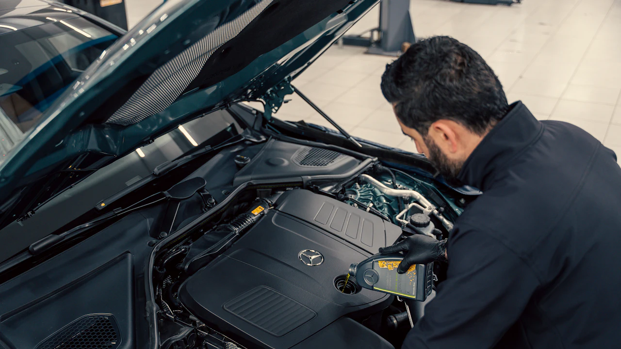 Technician inspecting the engine bay of a Mercedes-Benz in a workshop
