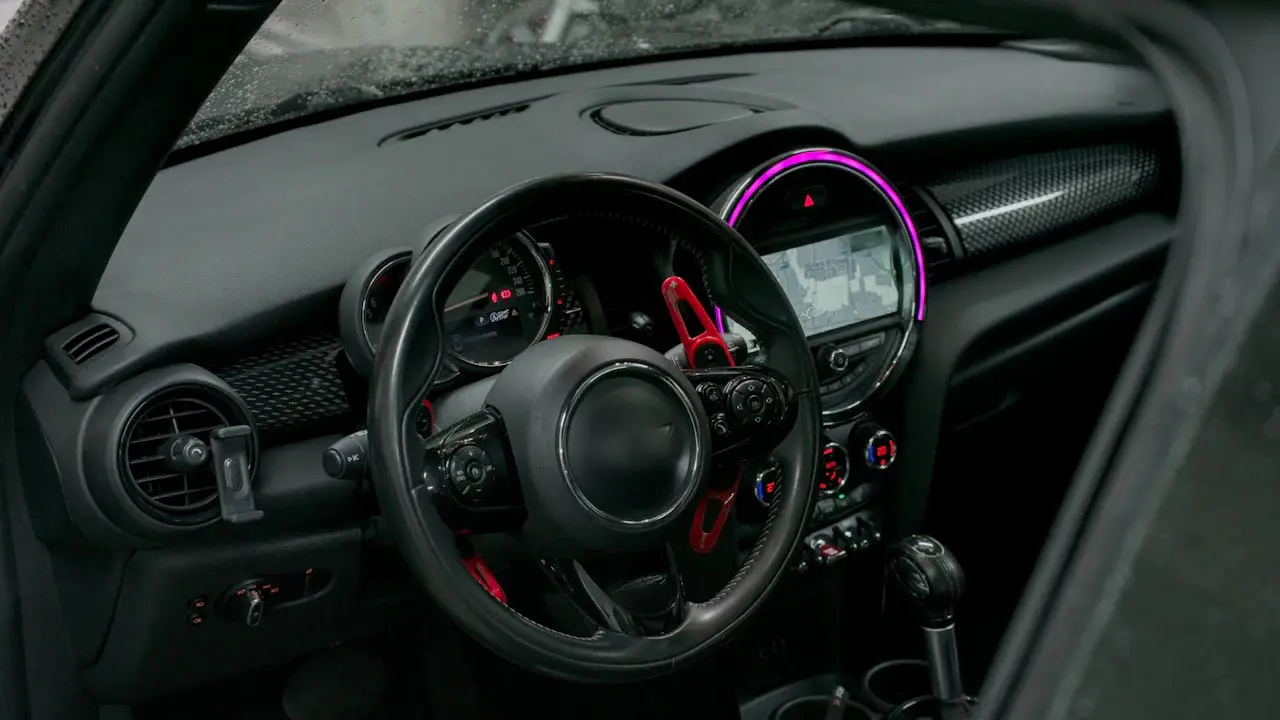 The cockpit of a MINI Cooper: steering wheel, round centre display ringed in light, and toggle switches.