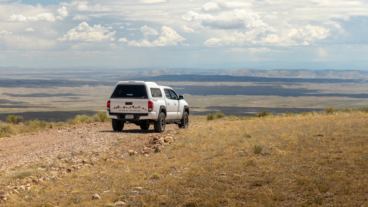 White pickup truck on dirt road overlooking vast arid landscape