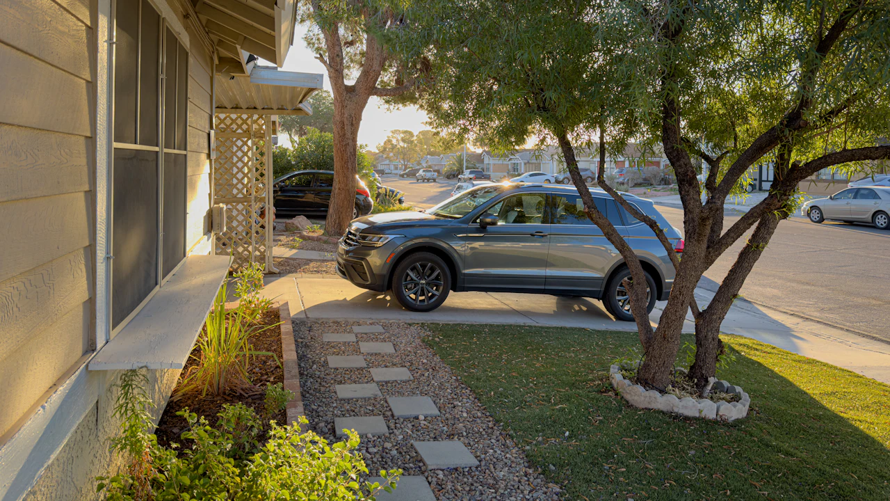a car parked in front of a house next to a tree