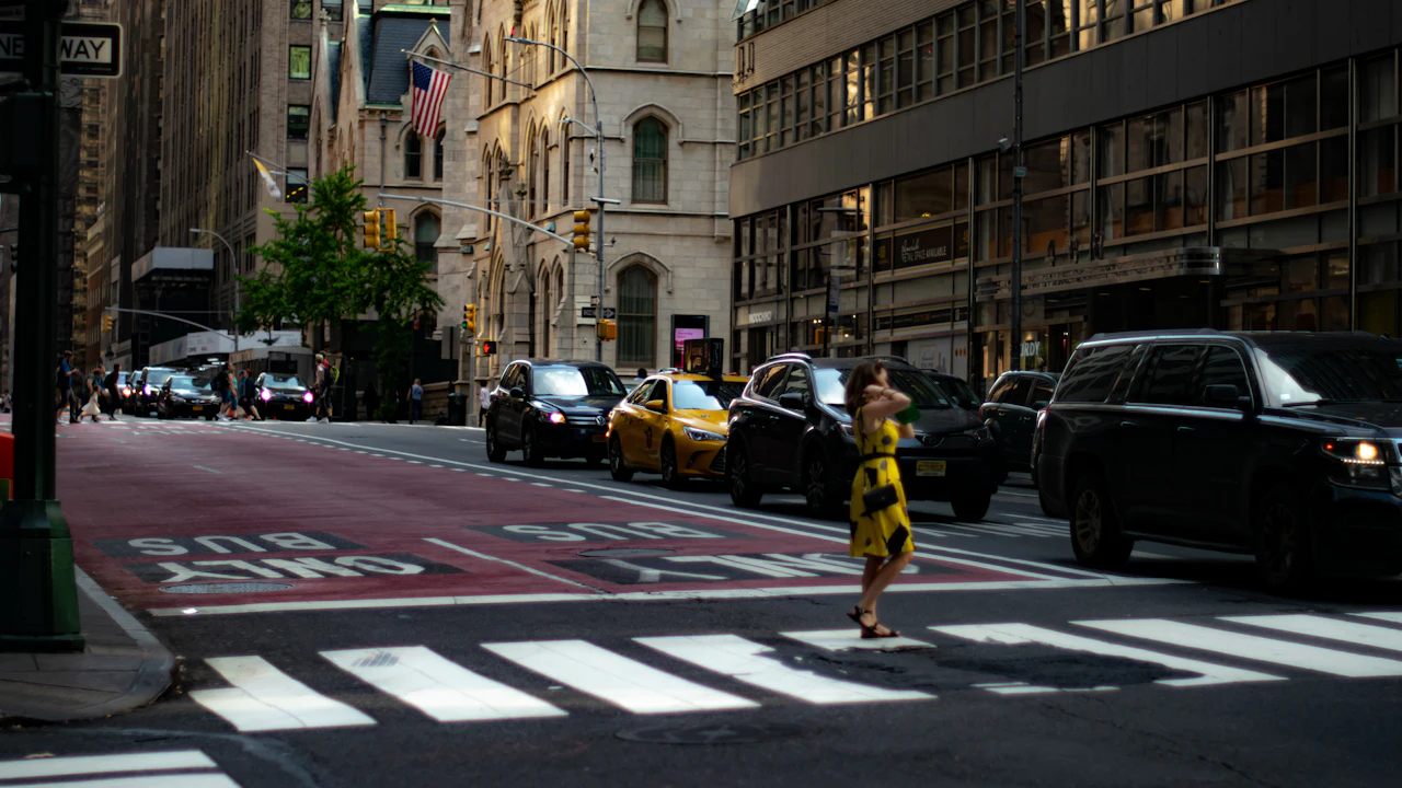 City-centre traffic at a crossing, a line of saloons and a yellow cab waiting at the lights