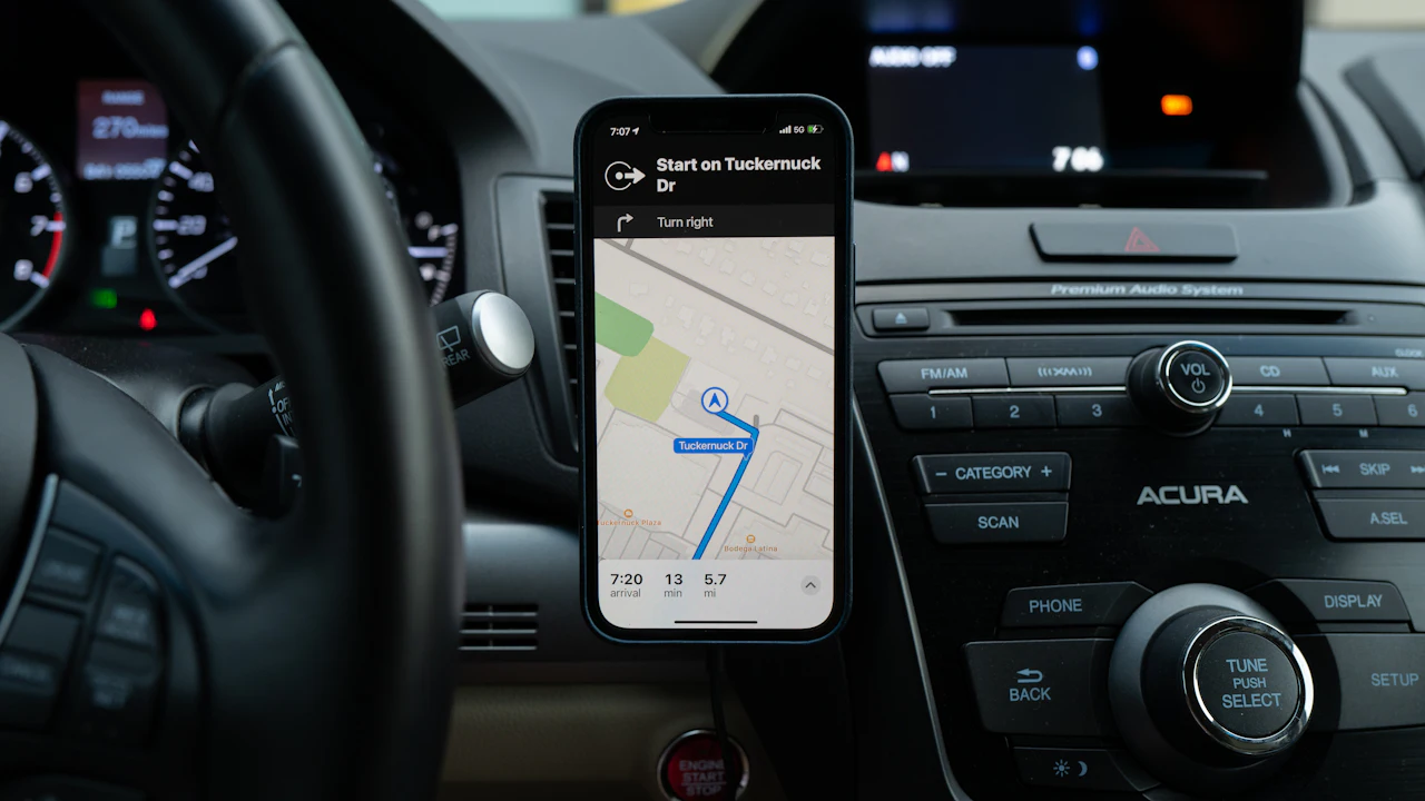 A phone mounted on a car dashboard showing a navigation app, with the car interior around it