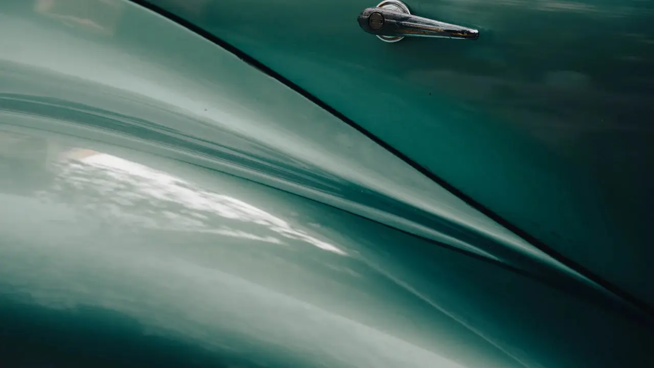A classic car’s door panel and body line catching the light.