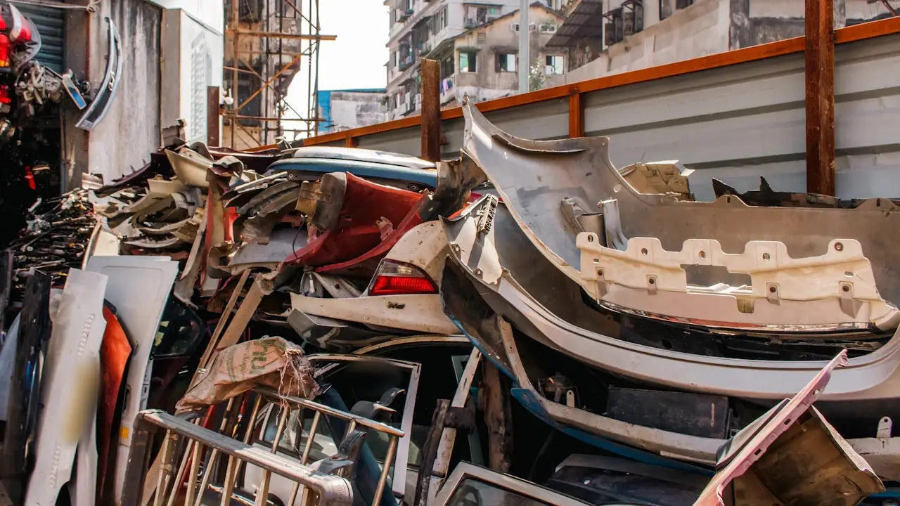 A heap of pulled car parts, bumpers and panels in a yard.