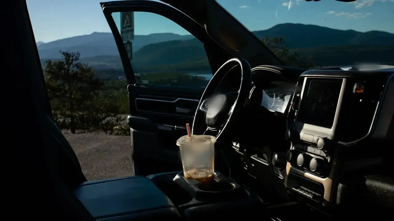 The cab of a pickup truck seen through the open driver's door: steering wheel, instrument cluster, centre touchscreen and climate-control knobs.