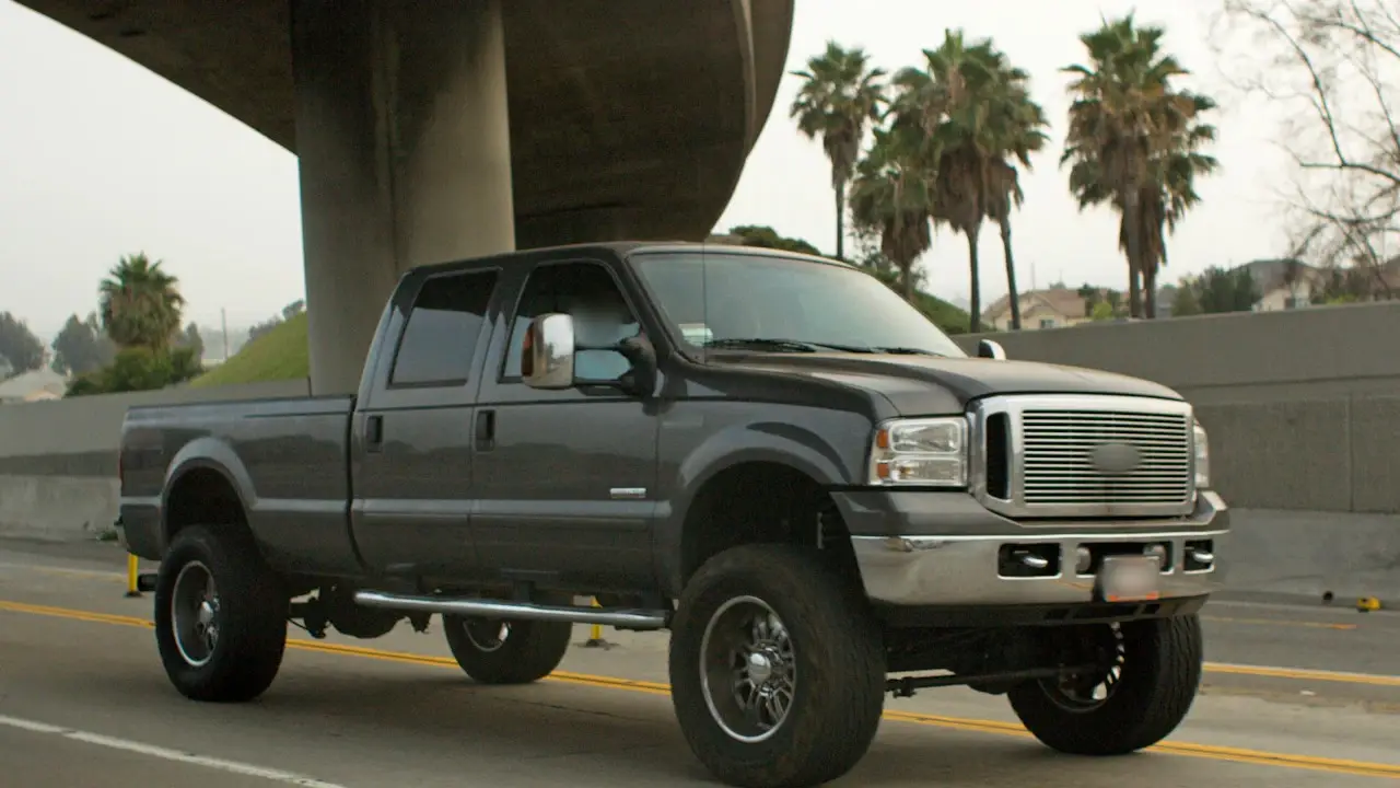 A lifted crew-cab pickup with side steps on a highway.