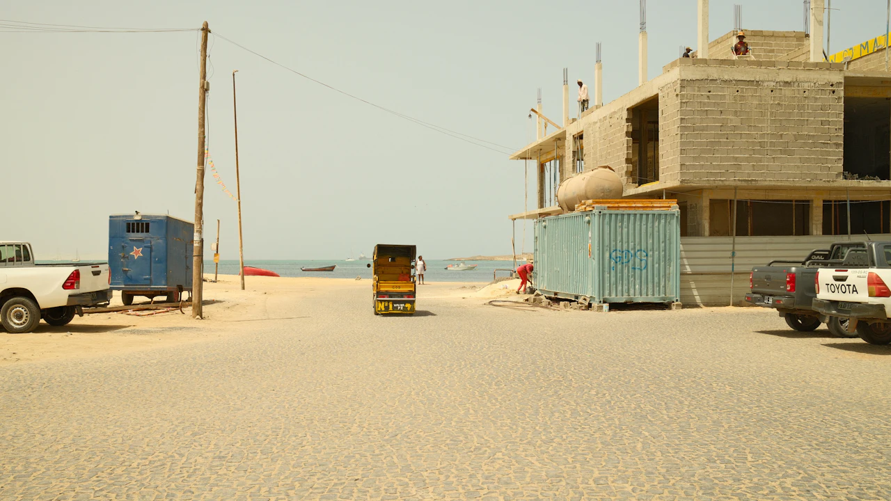Pickup trucks parked at a coastal building site with a part-built structure behind