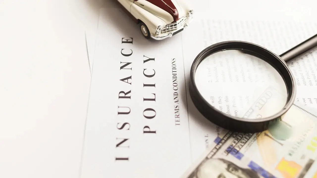 An insurance policy document with a magnifying glass, banknotes and a model car.