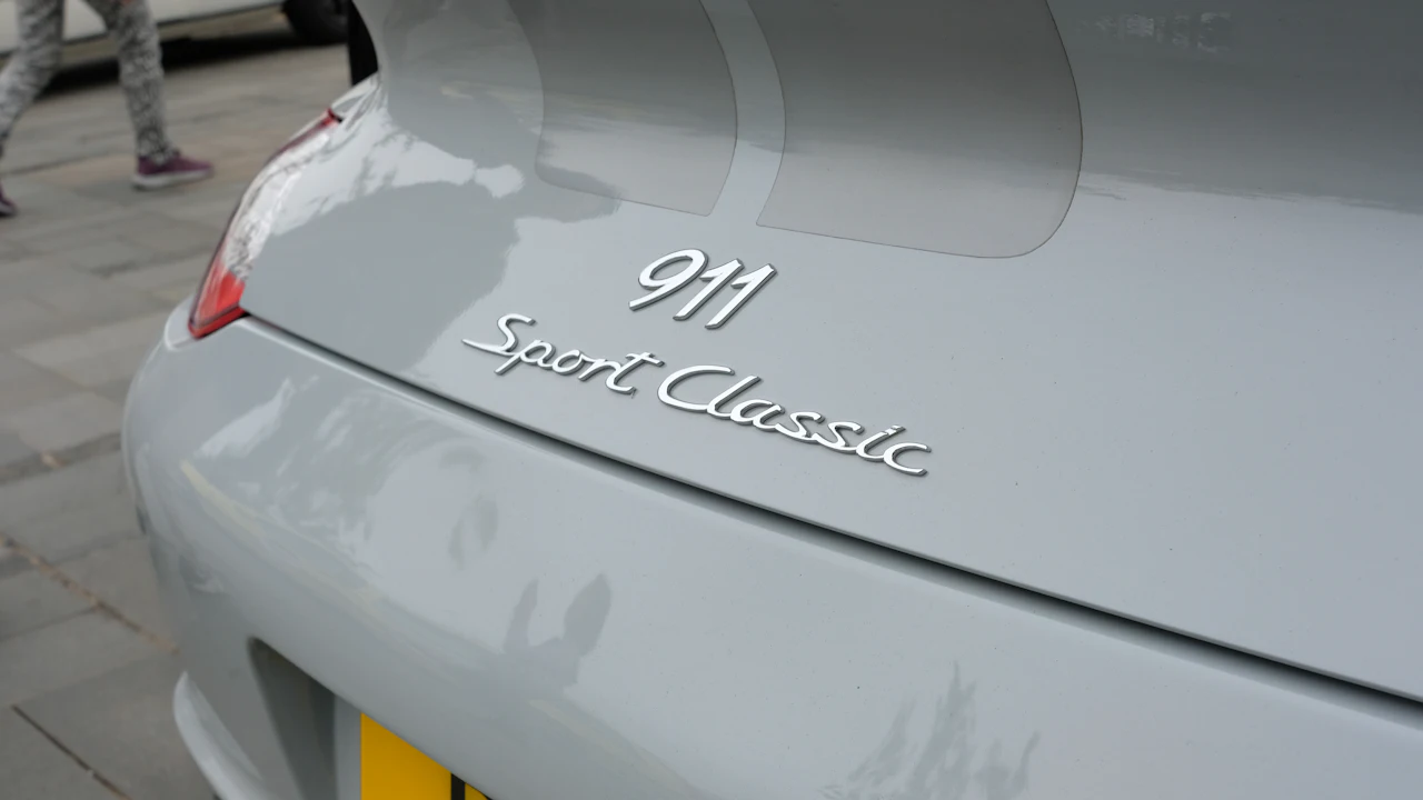 Chrome model script on the grey rear panel of a sports car, photographed close in daylight