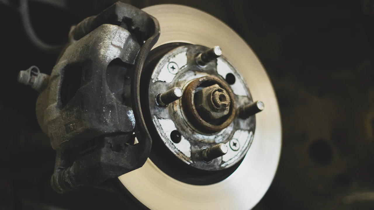 A brake disc and caliper with the wheel removed, showing the hub and wheel studs