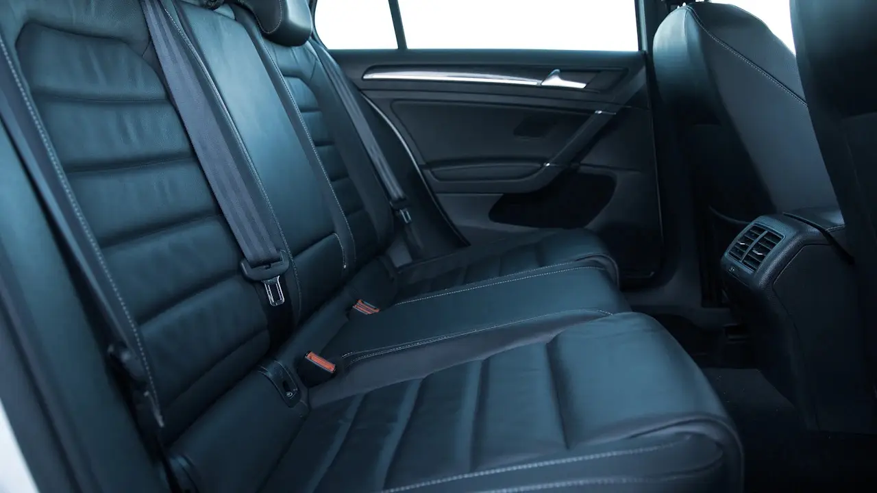 The black leather rear seats of a hatchback, seen through the open rear door.