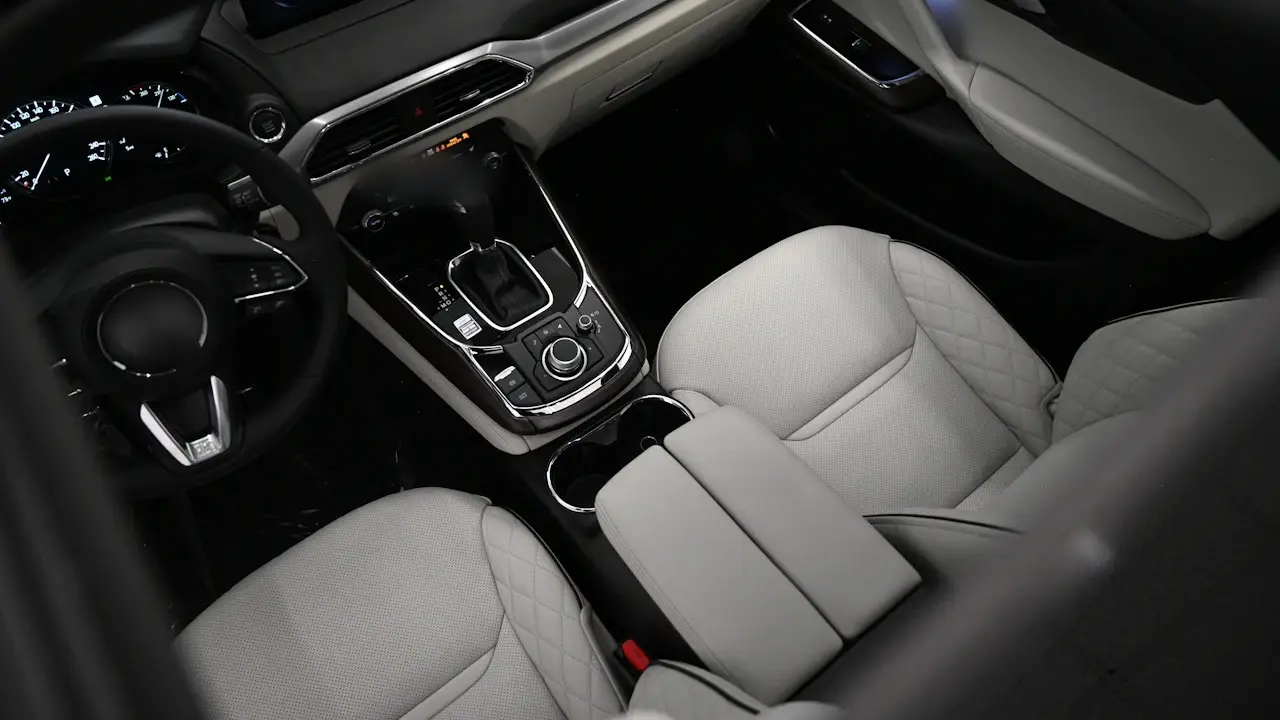 The light leather front seats, centre console and steering wheel of an SUV, seen from above.