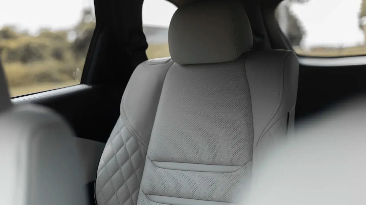 A light-grey quilted leather front seat seen through an open car door.