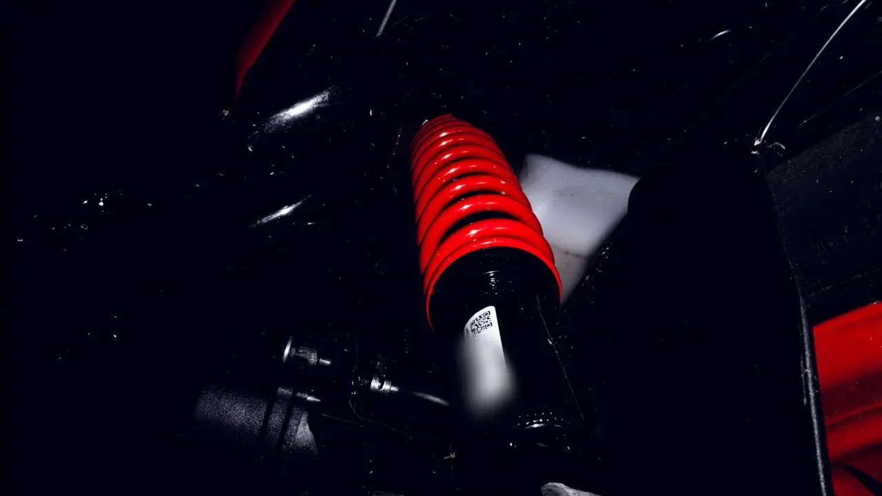 A red coil-spring shock absorber inside a car's wheel arch.