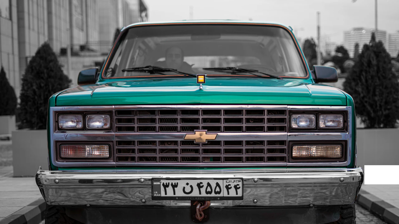 The front of a square-bodied green Chevrolet pickup photographed head-on, its chrome grille and gold bowtie badge filling the centre of the frame