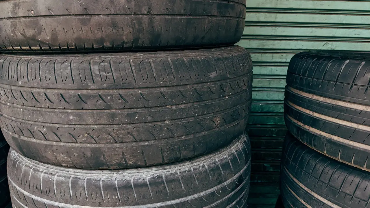 Stacks of used tires in front of a green roller door.