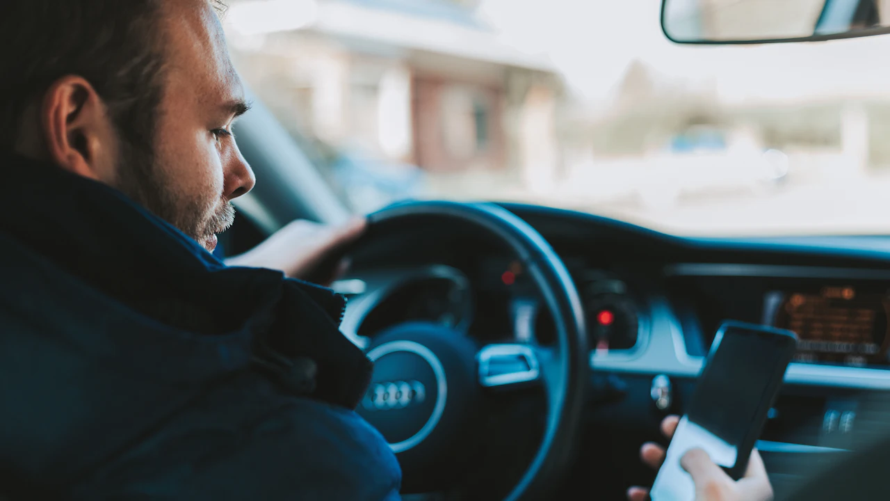 A person sitting in a car checking something on a smartphone