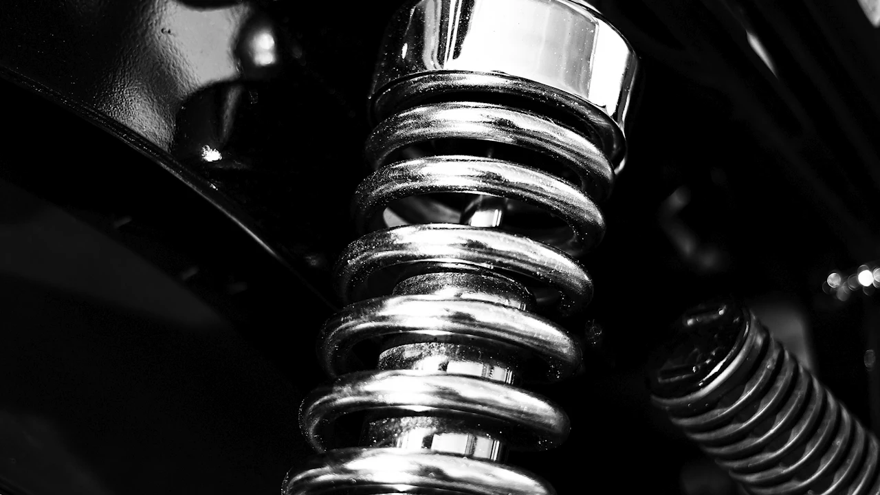 A coil spring wound around a shock absorber body, photographed close up in black and white